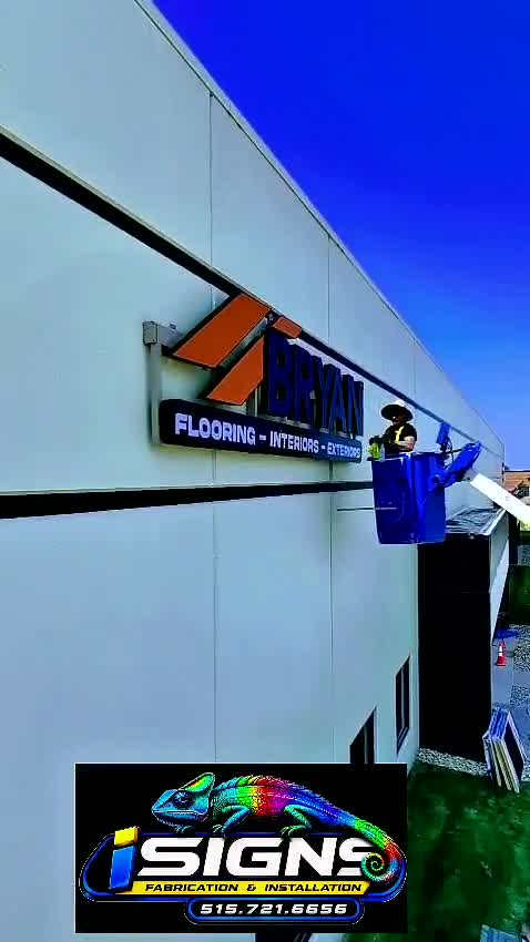 Installers fitting a building sign from a lift