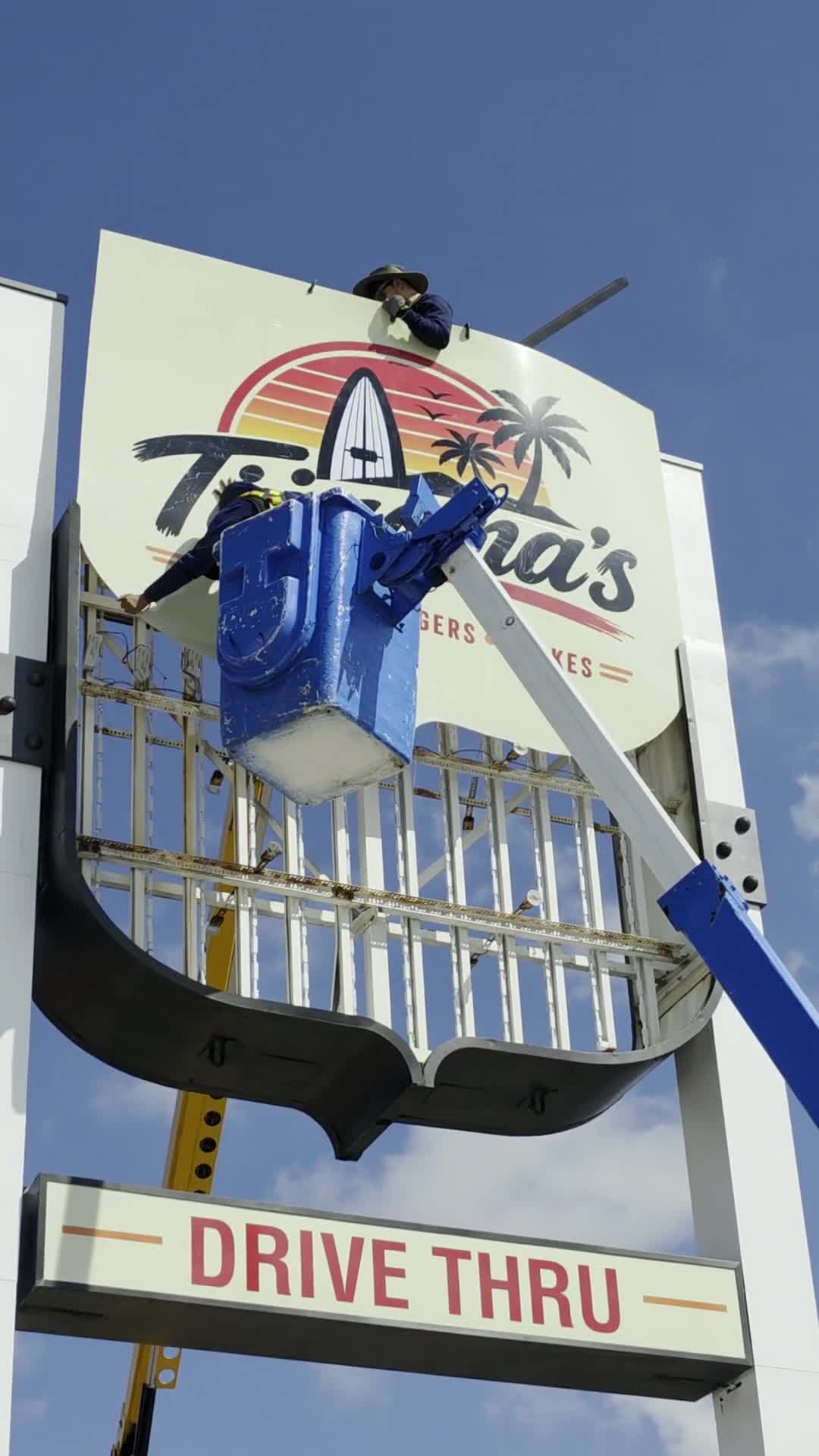 Installer working on a pole sign from a lift